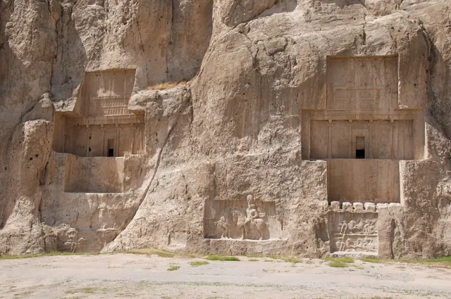 Two royal tombs cut into a cliff face, each with a cross-shaped facade and a carved relief above the door