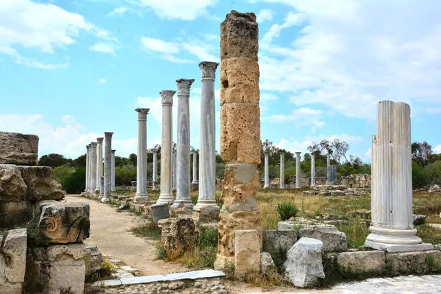 Rows of broken stone columns and walls of the ancient city of Salamis in Cyprus under a blue sky