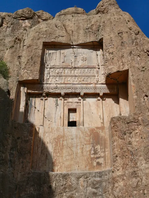 A rock-cut royal tomb with a carved facade high in a cliff face at Naqsh-e Rostam